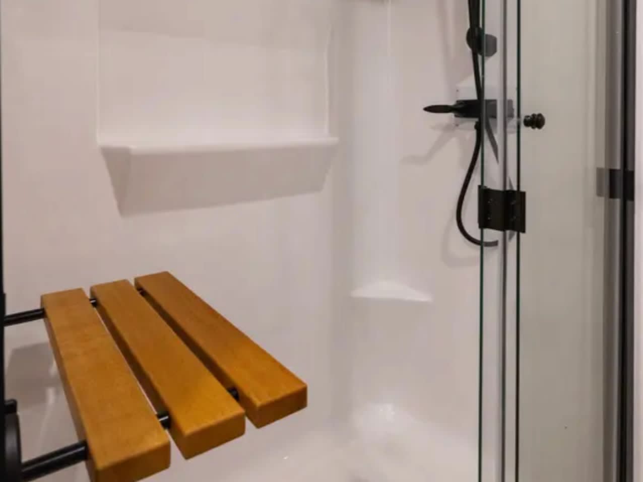 Walk-in shower with glass door and teak bench